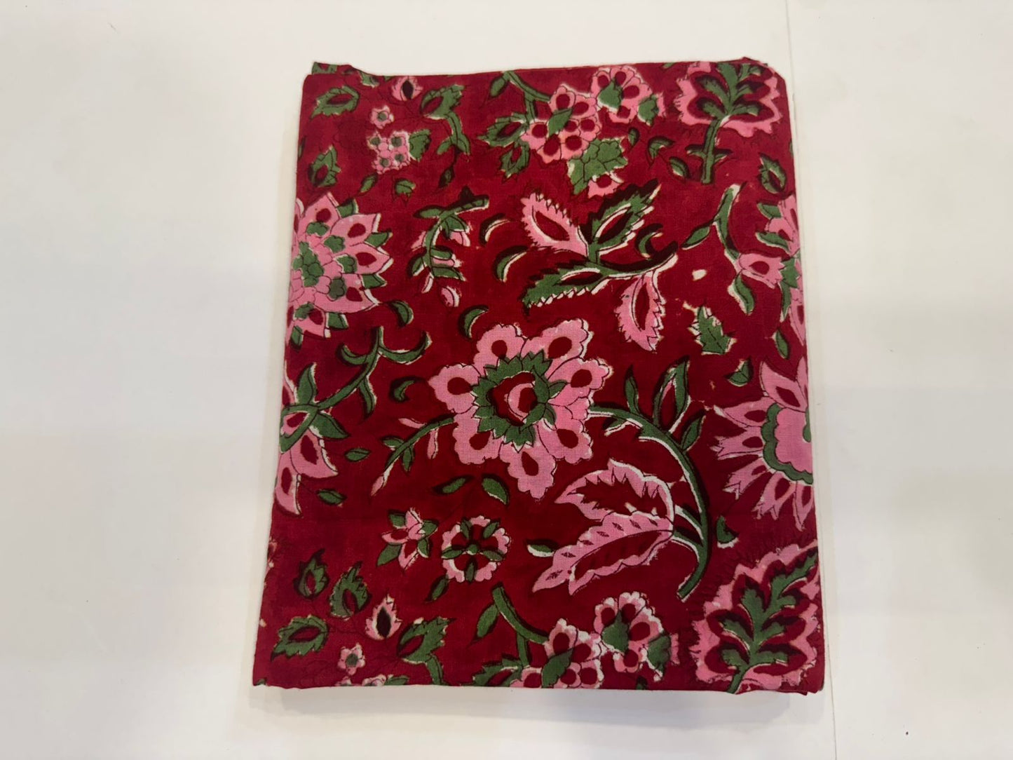 Red fabric with pink and green floral pattern on a white background