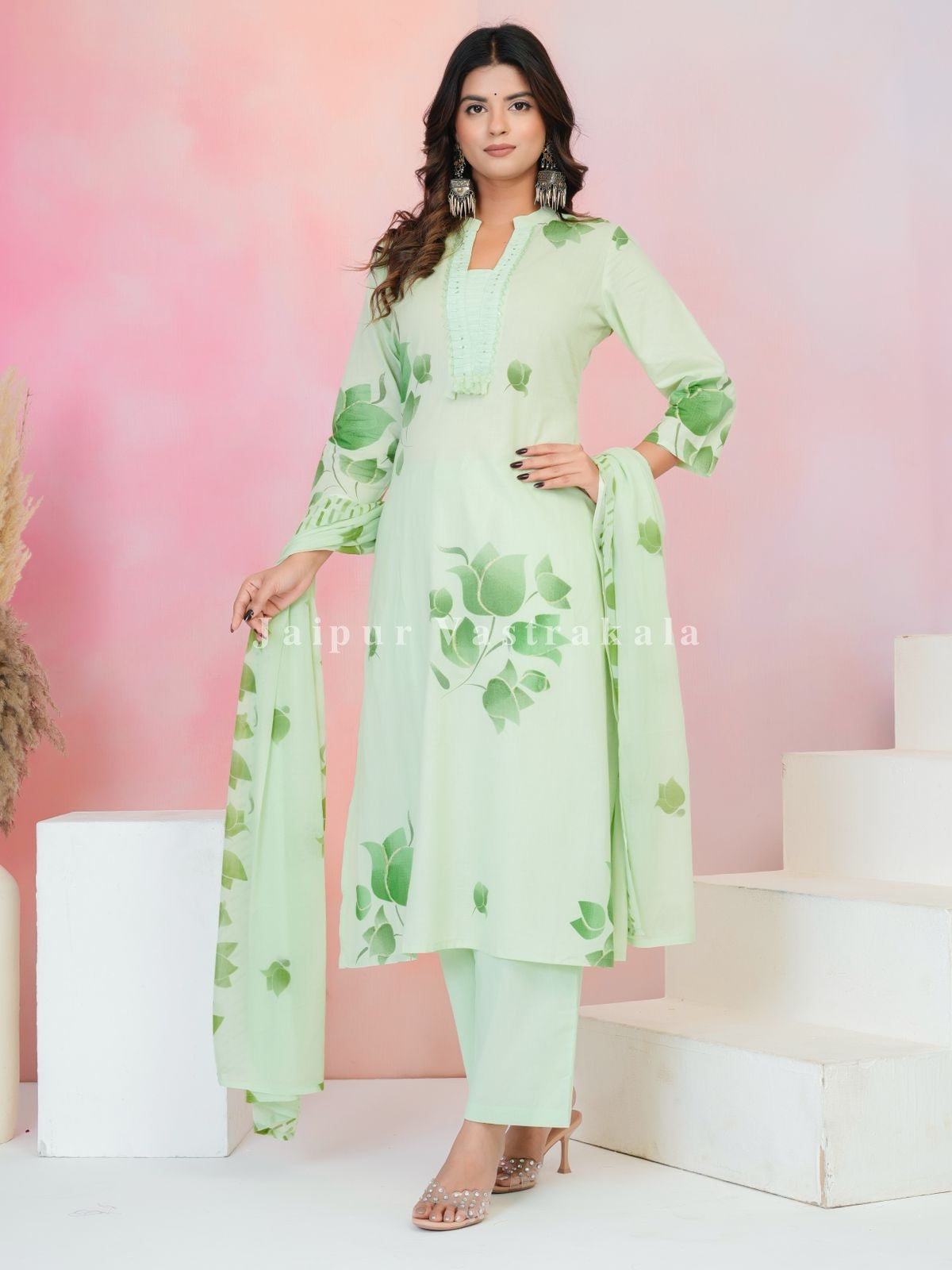 Woman wearing a light green floral dress with a pink background