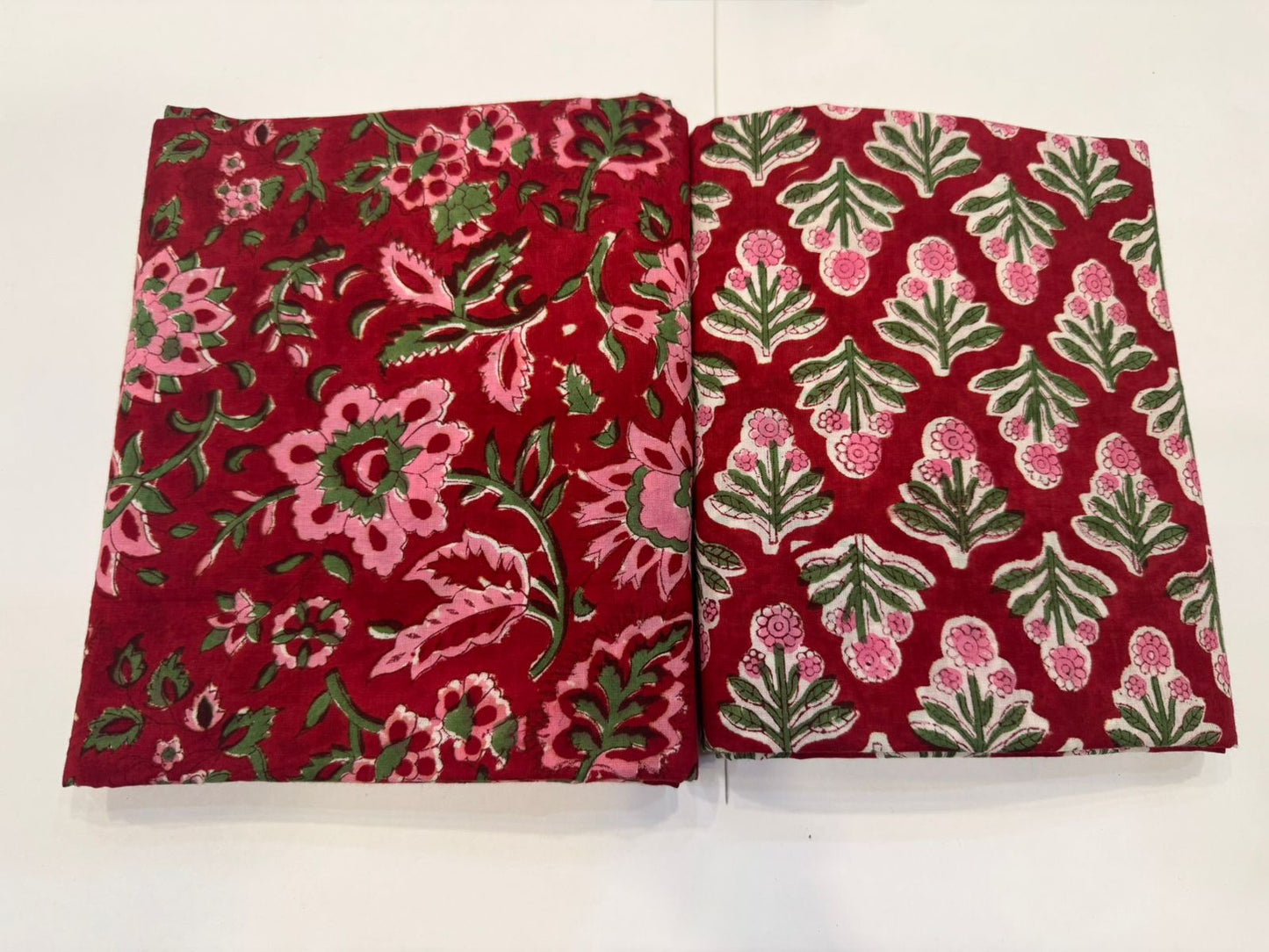 Two red fabric swatches with floral patterns on a white background
